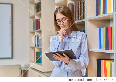 Portrait of student teenager girl using digital tablet inside classroom library Portrait of student teenager girl using digital tablet inside classroom library 124057402