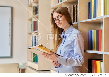 Portrait of student teenager girl holding textbooks inside classroom library 124057404