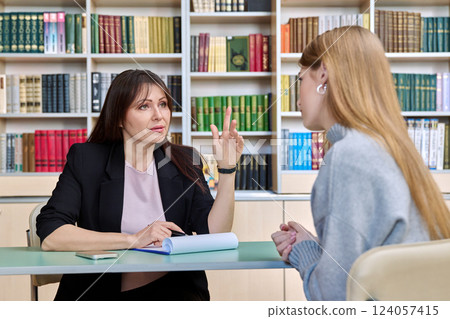Professional psychologist female working with young girl patient, sitting together in office Professional psychologist female working with young girl patient, sitting together in office 124057415