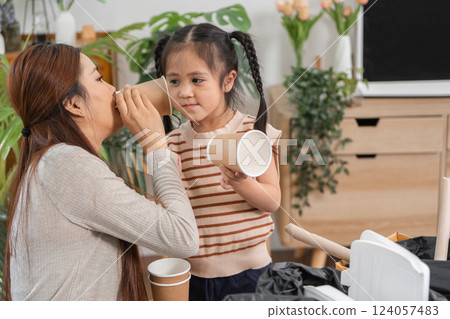 Engaging in Sustainability. A mother and daughter playfully sort recyclables for better waste management. 124057483