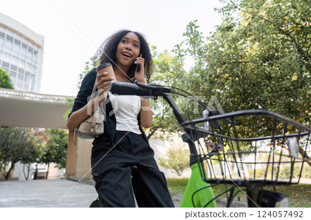 Lifestyle and Coffee Culture. A woman on a call with coffee in hand enjoying her bicycle ride through nature. 124057492