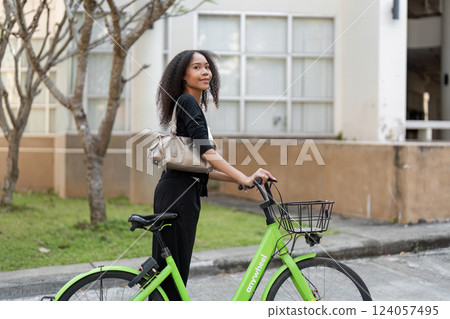 Cycling and Urban Lifestyle. A woman confidently holding her bicycle in a trendy city environment. 124057495