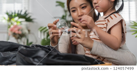 Recycling Education and Family Activities. A mother teaches her daughter about sorting recyclable materials. 124057499