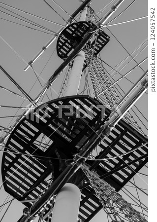 Vertical black and white photo of a ships mast, platform, and rigged ropes Vertical black and white photo of a ships mast, platform, and rigged ropes 124057542