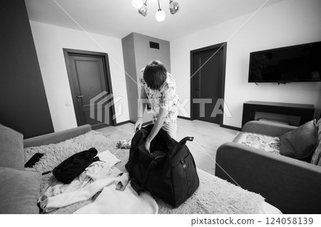 Packing for a journey in a cozy room with stylish decor and calm ambiance, as a young person prepares for travel amidst soft textiles and a minimalist design 124058139