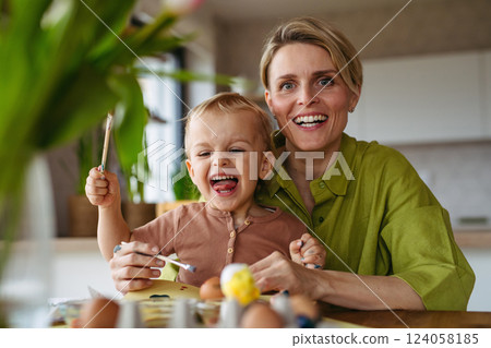 Mother and little son decorating easter eggs at home. Mother and little son decorating easter eggs at home. 124058185