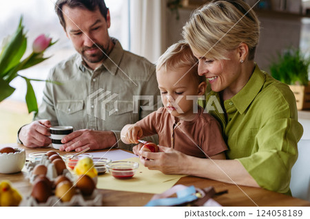 Little boy painting eggs with brush and easter egg dye. 124058189