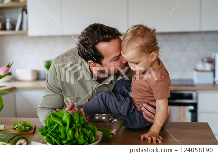 Dad and little boy preparing lettuce salad to celebrate Easter Green Thursday. Dad and little boy preparing lettuce salad to celebrate Easter Green Thursday. 124058190