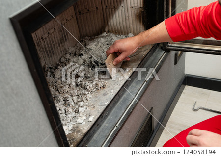 Cleaning the fireplace for cozy winter evenings and family gatherings in a modern home with a stylish design and warm ambiance Cleaning the fireplace for cozy winter evenings and family gatherings in a modern home with a stylish design and warm ambiance 124058194