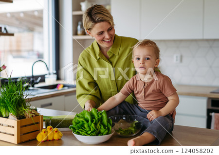 Mom and little boy preparing lettuce salad to celebrate Easter Green Thursday. 124058202