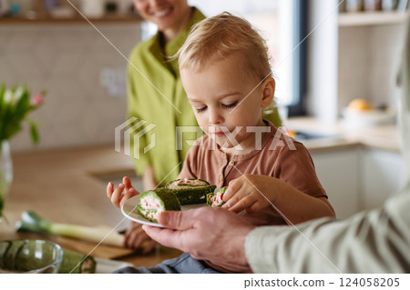 Boy eating green spinach roulade as tradition on Easter Green Thursday. 124058205