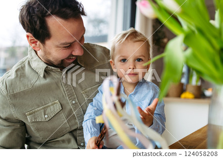 Father and little boy holding easter whip from willow branches, decorated with ribbons. Father and little boy holding easter whip from willow branches, decorated with ribbons. 124058208