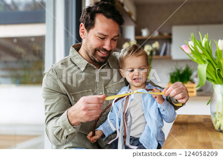 Father and little boy braiding easter whip from willow branches. Easter tradition concept. Father and little boy braiding easter whip from willow branches. Easter tradition concept. 124058209