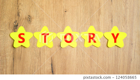 Story symbol. Concept word Story on beautiful yellow paper stars. Beautiful wooden table wooden background. Business lifestyle story concept. Copy space. 124058665