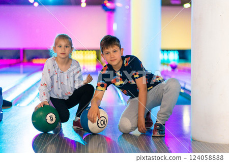 Two Young choldren girl boy siblings having fun and playing bowling Two Young choldren girl boy siblings having fun and playing bowling 124058888