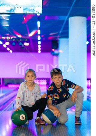 Two Young choldren girl boy siblings having fun and playing bowling Two Young choldren girl boy siblings having fun and playing bowling 124058890
