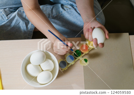 Painting Easter egg with green paint, close-up. Painting Easter egg with green paint, close-up. 124059580