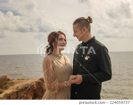 Beautiful lovers stand against the sky and sea and look at each other 124059737