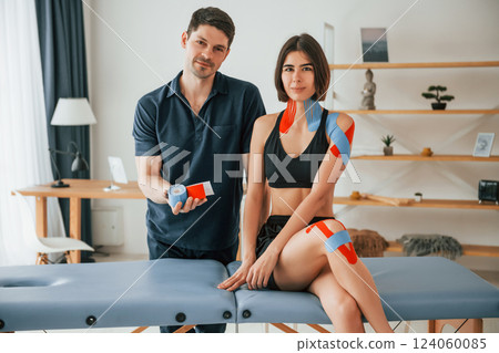 Beautiful portrait. Finished result. Woman visiting physiologist that putting kinesio tape on the skin Beautiful portrait. Finished result. Woman visiting physiologist that putting kinesio tape on the skin 124060085