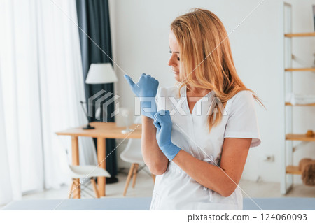 Wearing gloves. Female doctor in white coat is standing in the clinic 124060093