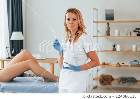Holding stick with gel. Woman is having sugaring procedure in the clinic by female doctor Holding stick with gel. Woman is having sugaring procedure in the clinic by female doctor 124060113