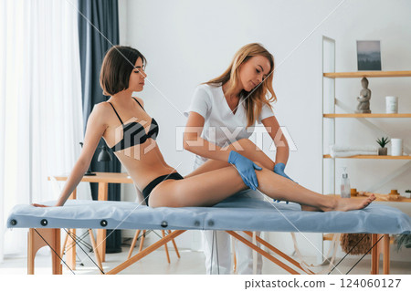 Working with legs. Woman is having sugaring procedure in the clinic by female doctor 124060127