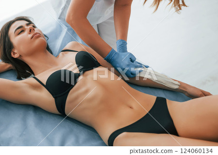 Putting cream on the hands. Woman is having sugaring procedure in the clinic by female doctor Putting cream on the hands. Woman is having sugaring procedure in the clinic by female doctor 124060134