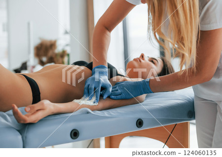 Woman is having sugaring procedure in the clinic by female doctor 124060135