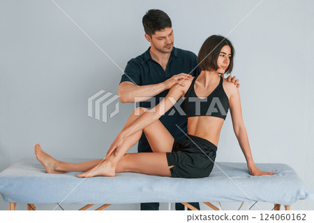Grey colored background. Woman visiting physiologist that making massages and helping with traumas Grey colored background. Woman visiting physiologist that making massages and helping with traumas 124060162