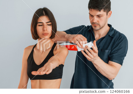 Focused worker. Woman visiting physiologist that putting kinesio tape on the skin 124060166