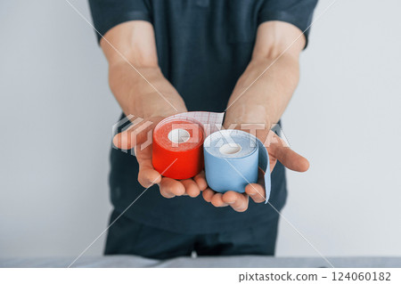 Showing product. Professional physiotherapist is standing indoors with kinesio tape Showing product. Professional physiotherapist is standing indoors with kinesio tape 124060182