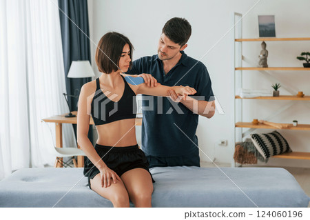 Modern background. Woman visiting physiologist that putting kinesio tape on the skin 124060196