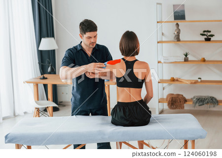 Modern background. Woman visiting physiologist that putting kinesio tape on the skin 124060198