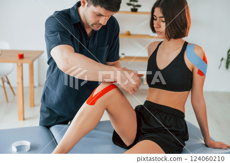 Side view. Woman visiting physiologist that putting kinesio tape on the skin 124060210