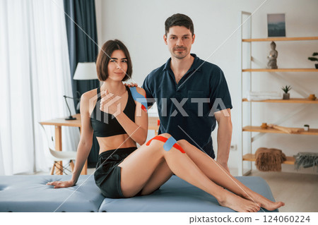 Finished result. Woman visiting physiologist that putting kinesio tape on the skin 124060224