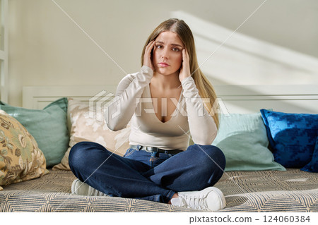 Sad worried sorrowful young woman sitting on couch at home. 124060384