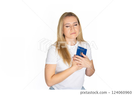 Sad angry blonde ukrainian woman in white t-shirt holding ukrainian passport isolated white background with sad face, negative down rejection concept 124060960