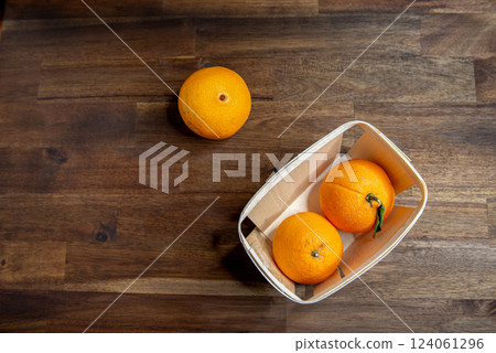 ripe unpeeled oranges in a wooden box on a brown wooden table. ripe unpeeled oranges in a wooden box on a brown wooden table. 124061296