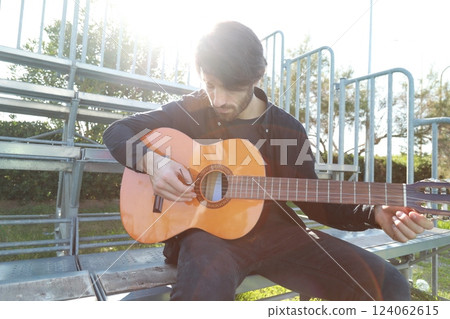 Man Tunes Guitar With Tuning Fork Outside 124062615