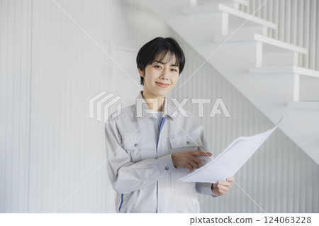 一位身著工作服的女士在倉庫裡查看圖紙 124063228