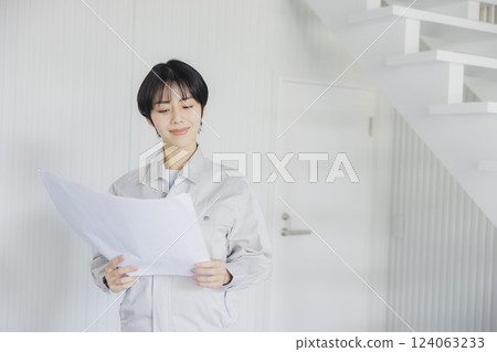 一位身著工作服的女士在倉庫裡查看圖紙 124063233