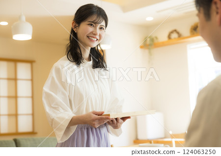 A woman in the living room carrying tea A woman in the living room carrying tea 124063250