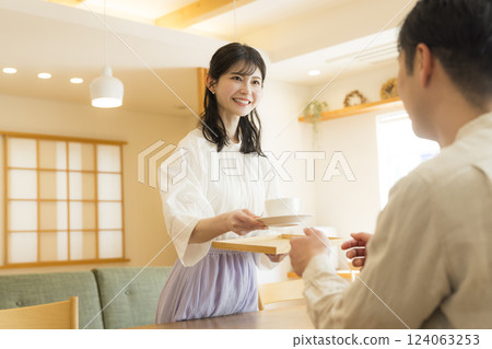 A woman in the living room carrying tea A woman in the living room carrying tea 124063253