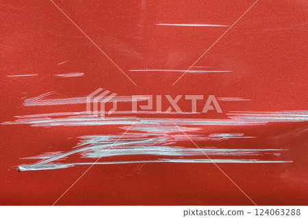 Close up of a red car with multiple visible scratches and paint damage The scratches expose the underlying metal, creating a contrast against the glossy surface. Perfect for automotive damage concepts 124063288