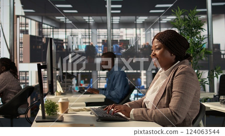 Focused african american general manager multitasking at desk to solve business tasks and operations on computer and documents. Woman meeting deadlines while making strategic decisions. Camera B. Focused african american general manager multitasking at desk to solve business tasks and operations on computer and documents. Woman meeting deadlines while making strategic decisions. Camera B. 124063544