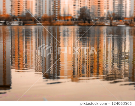 Calm water surface in an urban environment with tall multi-story buildings reflected in autumnal season. High rise buildings. Cityscape view in fall. Calm water surface in an urban environment with tall multi-story buildings reflected in autumnal season. High rise buildings. Cityscape view in fall. 124063565