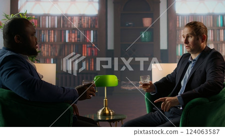 Gallant investor consultant engage in a meaningful conversation with a friend, enjoying a fine scotch and making propositions for a new business opportunity at the elite social club. Camera A. 124063587