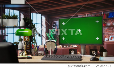 Isolated screen mockup PC on home office desk with stationary items and headphones on, surrounded by plants. Chroma key computer display in loft with shelves filled with books in background 124063627
