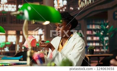 African american students team examining teeth for dentistry thesis, working together on stomatology research in the campus library. Man and woman preparing for their career. Camera B. African american students team examining teeth for dentistry thesis, working together on stomatology research in the campus library. Man and woman preparing for their career. Camera B. 124063658