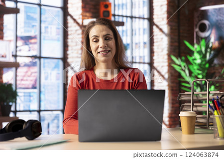Confident woman solving her tasks on a freelance platform at home, answering emails and multitasking. Person staying connected and enjoying the flexibility of working from home. 124063874